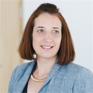 Frances Bailey in a pale blue jacket, in front of a door