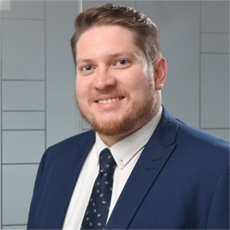 Matthew Saunderson in a blue suit and tie, in front of a geometric glass background
