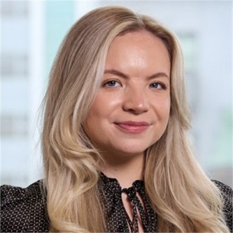 Rachel Forster in a black geometric patterned top, in front of a window