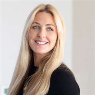 Katy Fisk in a black top, in front of a pale background