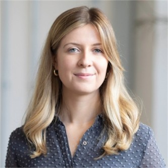 Eliza Bruton in a grey shirt, in front of a pale background