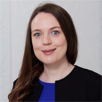 Ellen Wilkinson in a black jacket and blue top, in front of a pale background