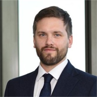 Anthony Cule in a dark suit and tie, in front of a window
