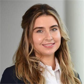 Rebecca Latham in a black jacket and white shirt, in front of a grey background